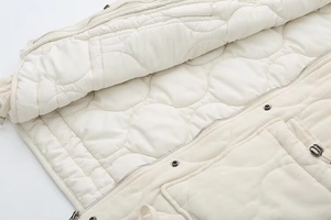 Detailed close-up of interior circular quilting and metal zipper on this cream vest