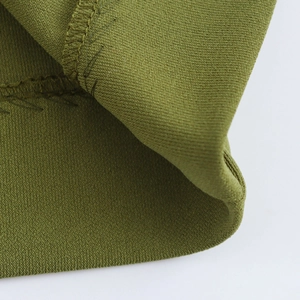 Macro detail of olive green knit dress showing high-quality stitching and fabric texture