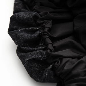 Detailed macro view of the elastic pleated hem and denim fabric splicing on the black dress