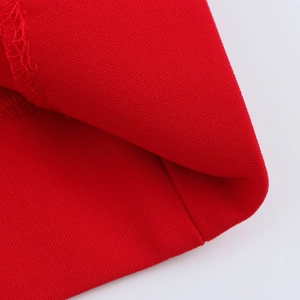 Close-up of bright red woven fabric texture with detailed stitching and hem finishing