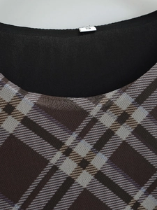 Détail du col rond avec étiquette taille S et tissu en maille à carreaux marron texturé