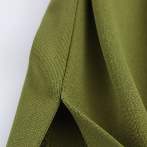 Close-up of olive green knitted fabric showing precision stitching and side slit detail