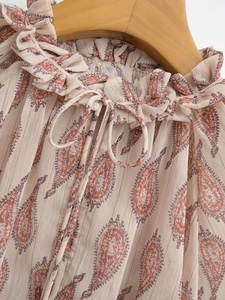 Close-up of paisley print blouse featuring ruffled collar and delicate drawstring ties