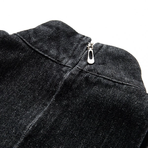 Close-up detail of silver metal zipper and washed black denim fabric on a sleeveless dress