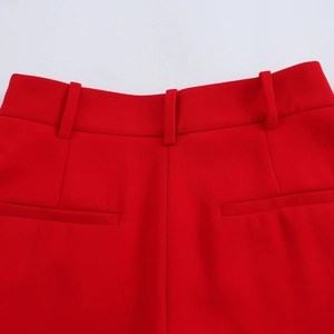 Detail of red high-waisted trousers featuring belt loops and tailored rear welt pockets