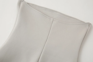 Detail view of double-stitched hem and light grey knitted fabric texture on the top