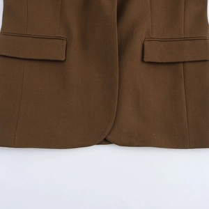 Detailed view of the dark brown twill blazer featuring symmetrical flap pockets and curved hem