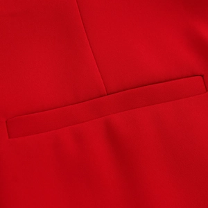 Detail shot of a red V-neck vest showing a precise welt pocket and vertical seams