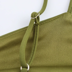 Macro detail of ribbed knit fabric and silver metal ring on olive green dress strap