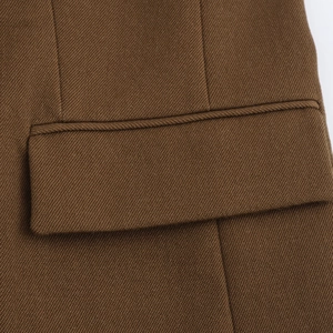 Detailed close-up of a brown twill blazer featuring a high-quality flap pocket and stitching