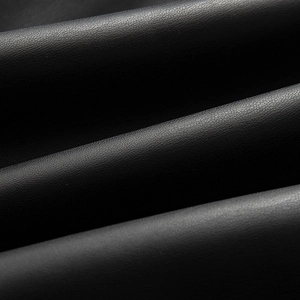 Macro shot of black PU leather texture with lychee grain pattern and subtle sheen
