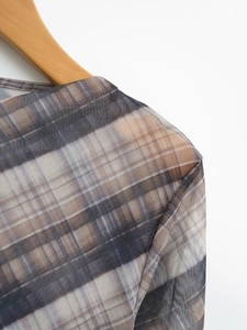 Detail of sheer mesh shoulder seam featuring a vintage brown and blue plaid pattern