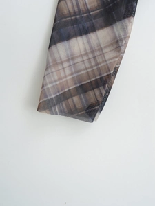 Close-up of translucent mesh fabric detail with classic vintage plaid pattern on sleeve cuff