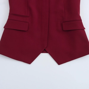Detailopname van bordeauxrood vest met fijne stoftextuur en scherpe driehoekige zoom