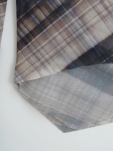 Detail of checkered mesh fabric with breathable texture and curved hemline finish
