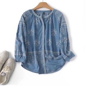 Detail of floral embroidery on light blue casual long-sleeved shirt with round neck
