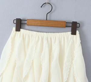 Detail of off-white lace trim and pleated chiffon fabric on the elastic waist skirt