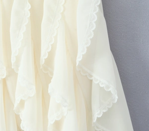 Detail of layered ruffles and delicate lace trim on a white chiffon skirt fabric