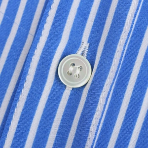 Vue détaillée du tissu à rayures bleues et du bouton blanc sur une chemise à manches longues