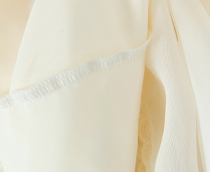 Detailed close-up of cream white lace skirt fabric showing high-quality stitching and seams