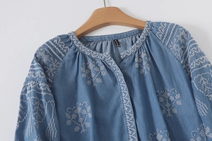 Detailed close-up of white floral embroidery on a navy blue long-sleeved casual cotton shirt