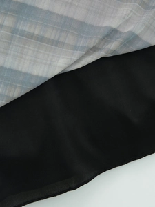 Gros plan du tissu en maille à carreaux géométriques et doublure noire sur la robe