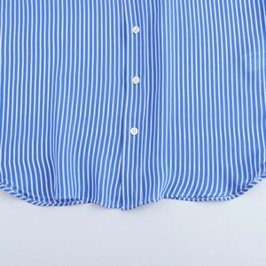 Détail d'une chemise à rayures bleues montrant la texture du tissu et l'ourlet boutonné