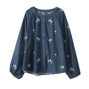 Détail de la broderie de tulipes blanches sur la chemise en denim bleu foncé à manches