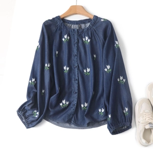 Détail de broderie florale sur une chemise en jean bleue à manches longues boutonnée
