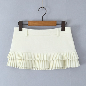 Detail of cream pleated mini skirt showing layered fabric textures and waistband on a hanger