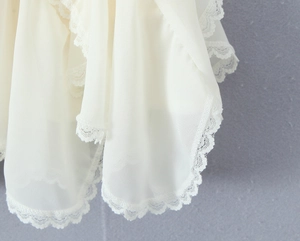Detail view of white chiffon skirt featuring delicate lace hem and elegant draping effect