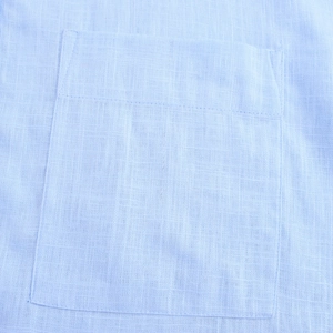 Vue détaillée de la texture du lin bleu clair avec une poche plaquée carrée aux coutures nettes