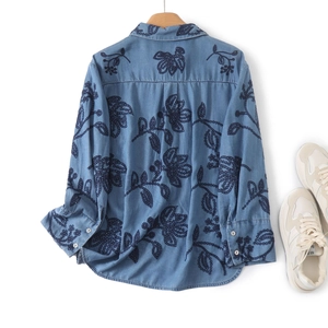 Gros plan sur la broderie florale bleue et la texture denim de la chemise en coton à manches