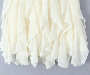 Detailed view of cream ruffled mini skirt featuring layered chiffon and delicate lace trims
