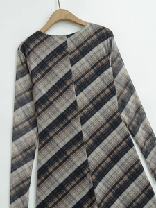 Détail d'un haut en tulle à carreaux marron et gris avec manches longues sur un cintre en bois