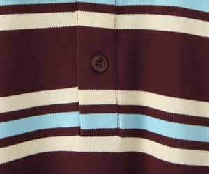 Dettaglio macro della polo in cotone piqué a righe con finiture bordeaux e azzurre a contrasto