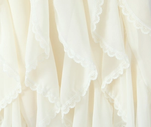 Detail shot of multi-layer ruffles with delicate lace trim on beige chiffon skirt