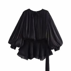 Detailed view of black satin puff sleeve top featuring elegant ruffle hem and tie-neck detail