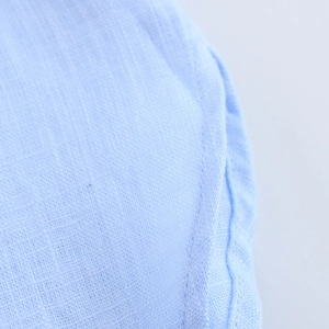 Détail de chemise en coton bleu clair montrant les coutures et la texture du tissu lin