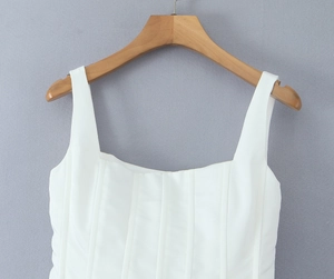 Detail of white square neck corset dress with structured vertical seams on a wooden hanger