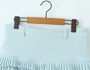Detail of light blue pleated mini skirt showing woven fabric texture and fine waistband