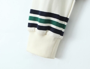 Detalle de la manga del polo crema con rayas verdes y azules y puños de punto acanalado