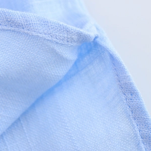 Gros plan sur la texture du lin bleu clair avec coutures précises sur la chemise