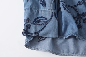 Détail de broderie florale sur denim bleu clair avec texture en sergé de qualité