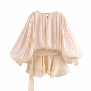 Detail view of champagne pleated mini dress featuring puffy sleeves and back waist tie