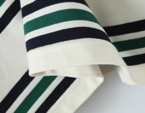 Primer plano del tejido de polo con rayas azul marino, verde y crema y textura de piqué