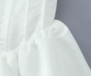 Detailed view of square neck corset stitching and vertical boning on the white dress