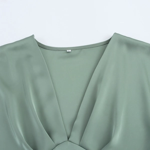 Gros plan d'une robe en satin vert sauge avec col en V montrant le tissu soyeux