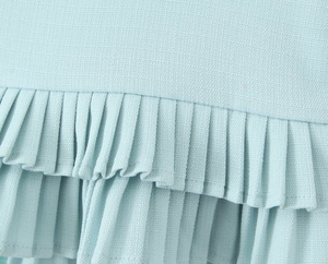 Detailed macro view of light blue pleated ruffles on a textured mini skirt fabric