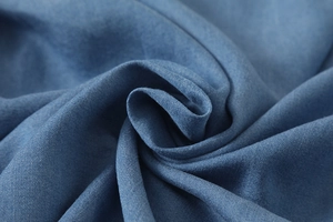 Close-up of soft blue twill fabric texture with rose-shaped fold and woven details